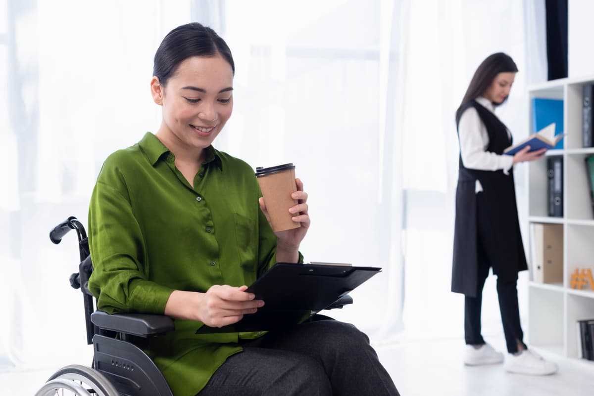 A diverse team of professionals collaborating in a modern office, one of whom is in a wheelchair, illustrating an inclusive workplace.